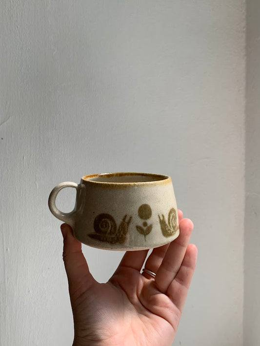 A mug in the sgraffito style held in a hand